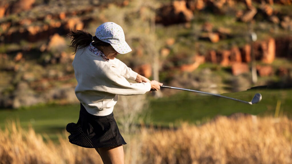 A woman golfing on a sunny evening.