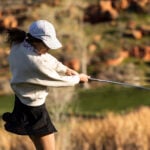 A woman golfing on a sunny evening.