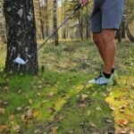 golfspelare slår golfslag från gräs bland lövträd