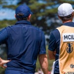 golfspelare och caddie på golfbana under golftävling