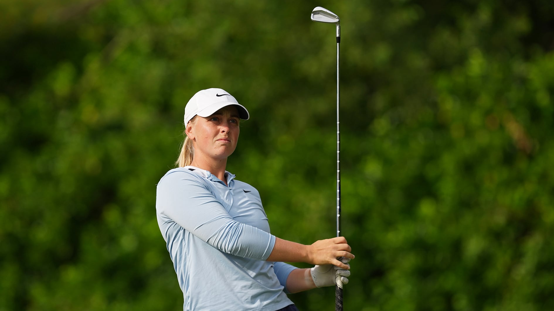 golfspelaren maja stark slår ett järnslag med en järnklubba på en golfbana