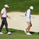 golfspelare och caddie på golfbana under golftävling