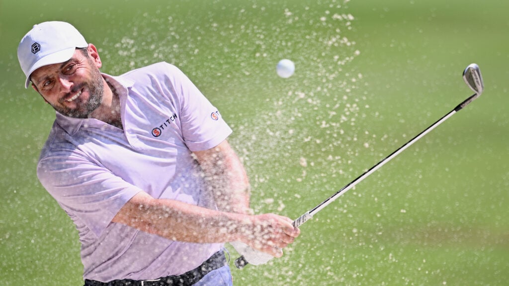 golfspelare slår sand och boll ur sandbunker