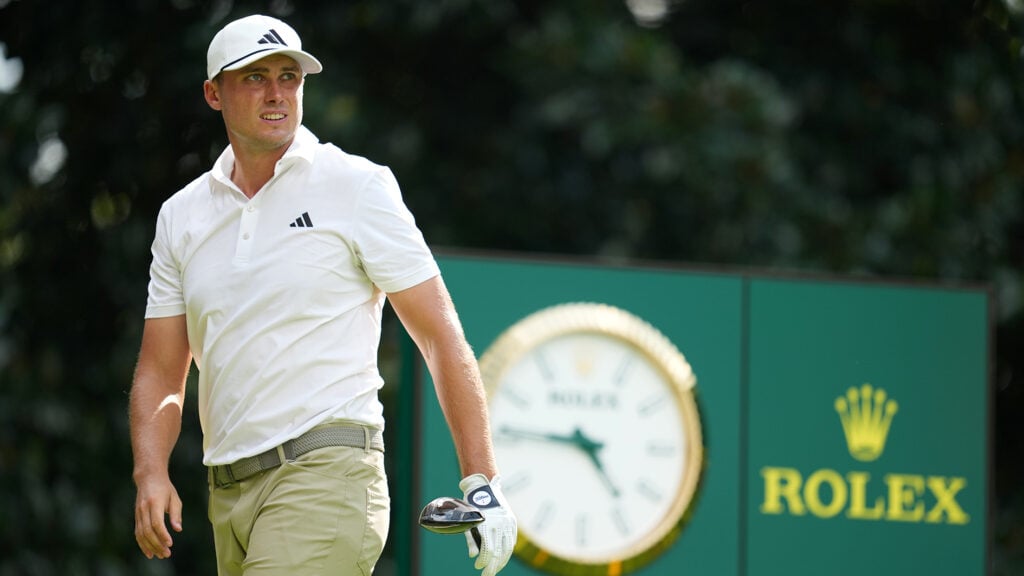 ludvig åberg tittar på golfslag på golfbana med klocka i bakgrunden