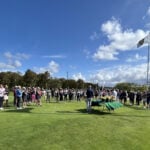 stor grupp människor samlas på en golfbana