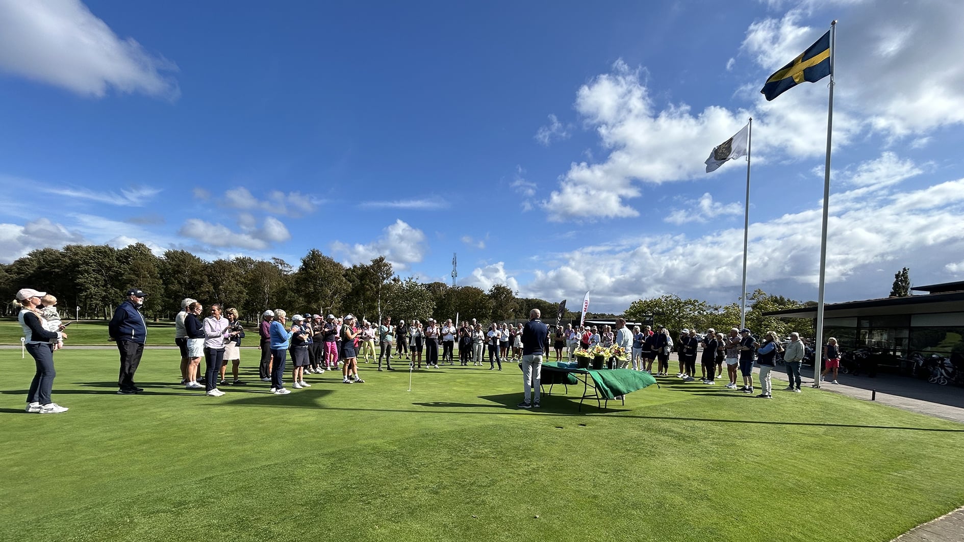 stor grupp människor samlas på en golfbana