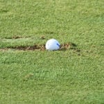 golfboll i uppslagen torv på golfbana