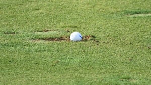 golfboll i uppslagen torv på golfbana