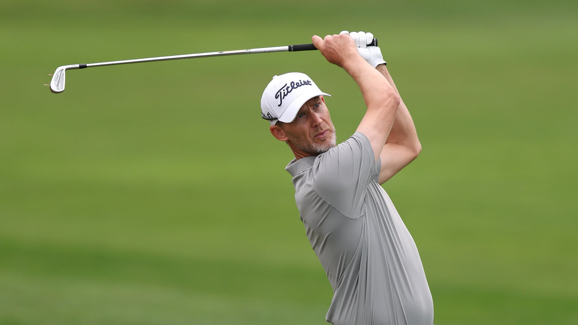 golfspelar med vit golfkeps på grön golfbana