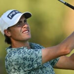 golfspelare i vit golfkeps och mönstrad golfpiké