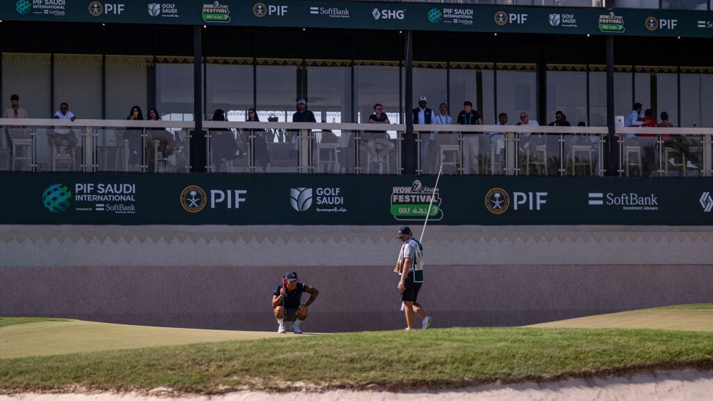golfspelar och caddie på golfbana i saudiarabien