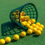 gula golfbollar, grön hink på grönt konstgräs
