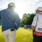 golfspelare och caddie på golfbana under golftävling