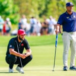 två golfspelare med putters på en golfgreen