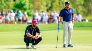 två golfspelare med putters på en golfgreen