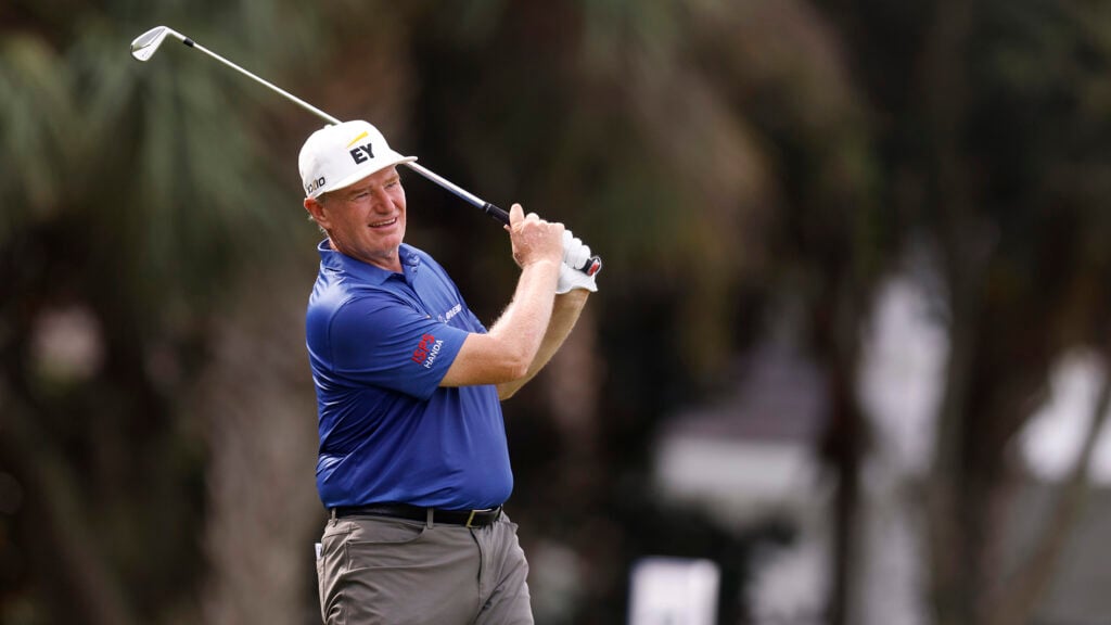 golfspelaren ernie els i blå golfpiké slå med järnklubba på golfbana
