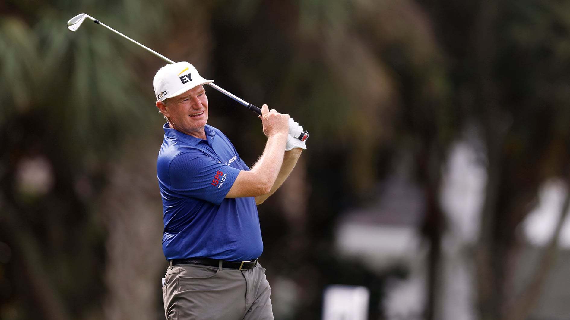 golfspelaren ernie els i blå golfpiké slå med järnklubba på golfbana