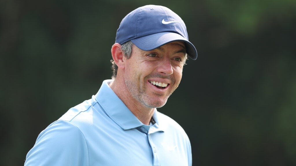 golfspelaren rory mcilroy i blåa golfkläder skrattar på en golfbana
