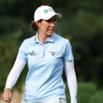 golfspelare i ljusa golfkläder på golfbana med många barrträd