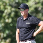 golfspelaren henrik stenson i svarta golfkläder på golfbana i USA med många lövträd
