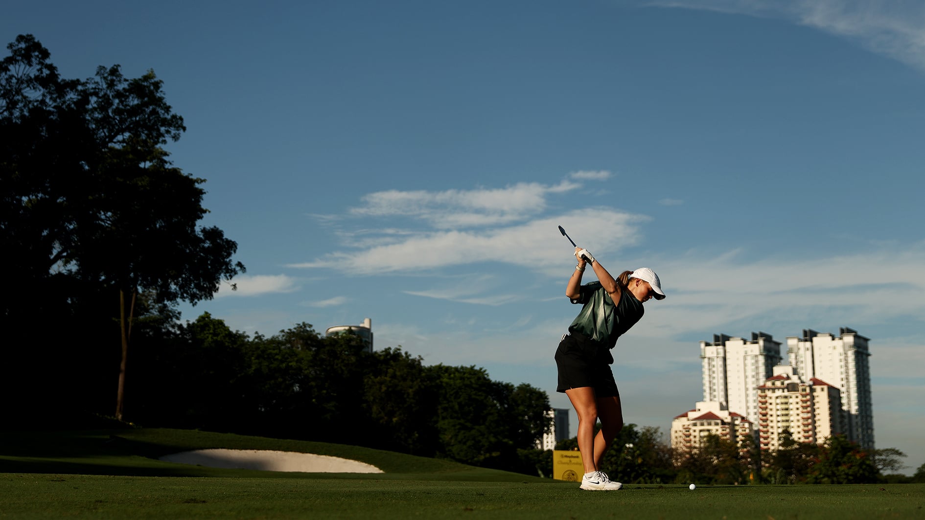golfspelare på golfbana med stadsvy i bakgrunden