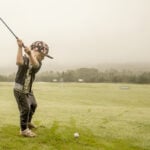 ung golfspelare svingar golfklubba på träningsyta