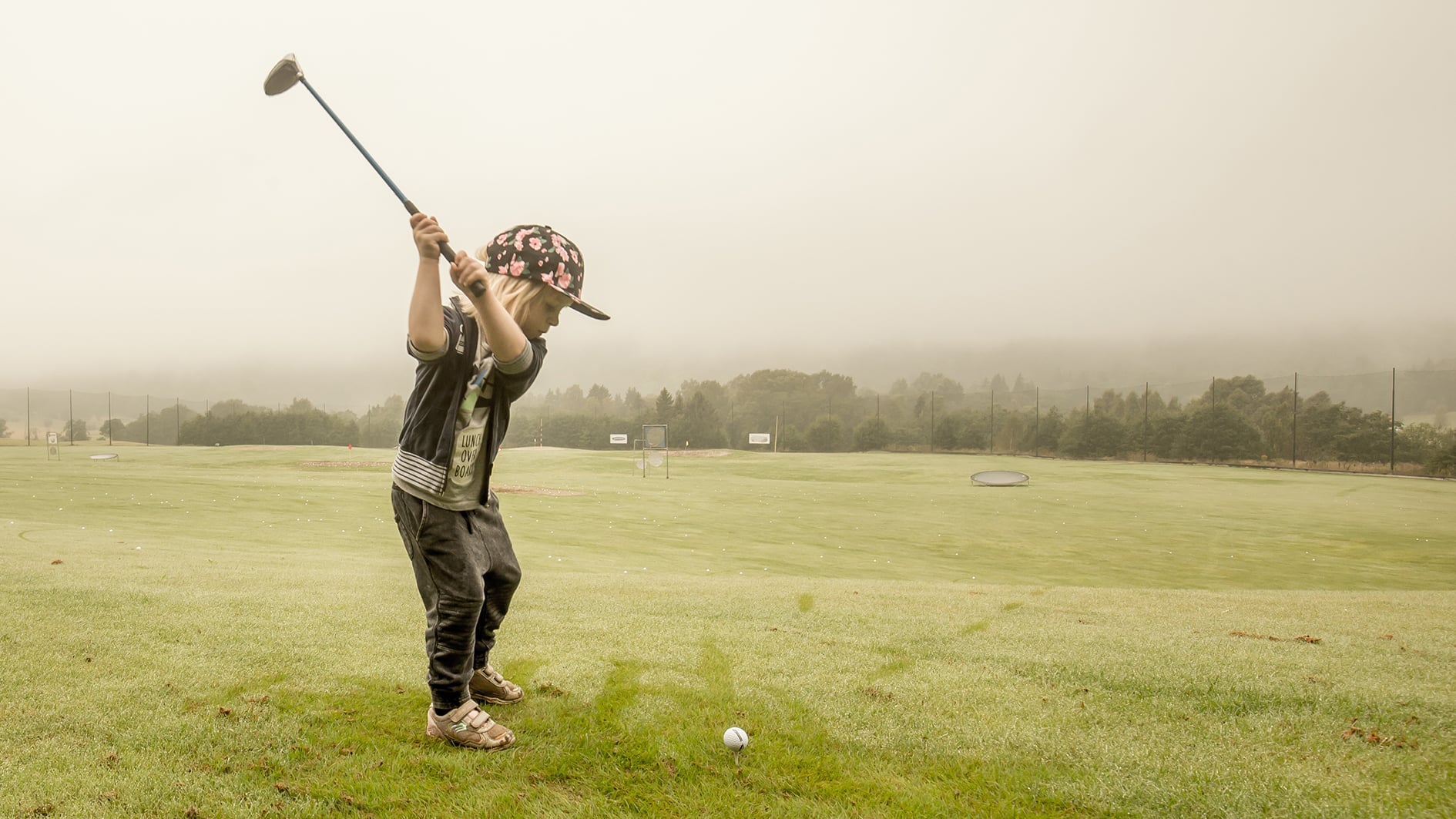 ung golfspelare svingar golfklubba på träningsyta